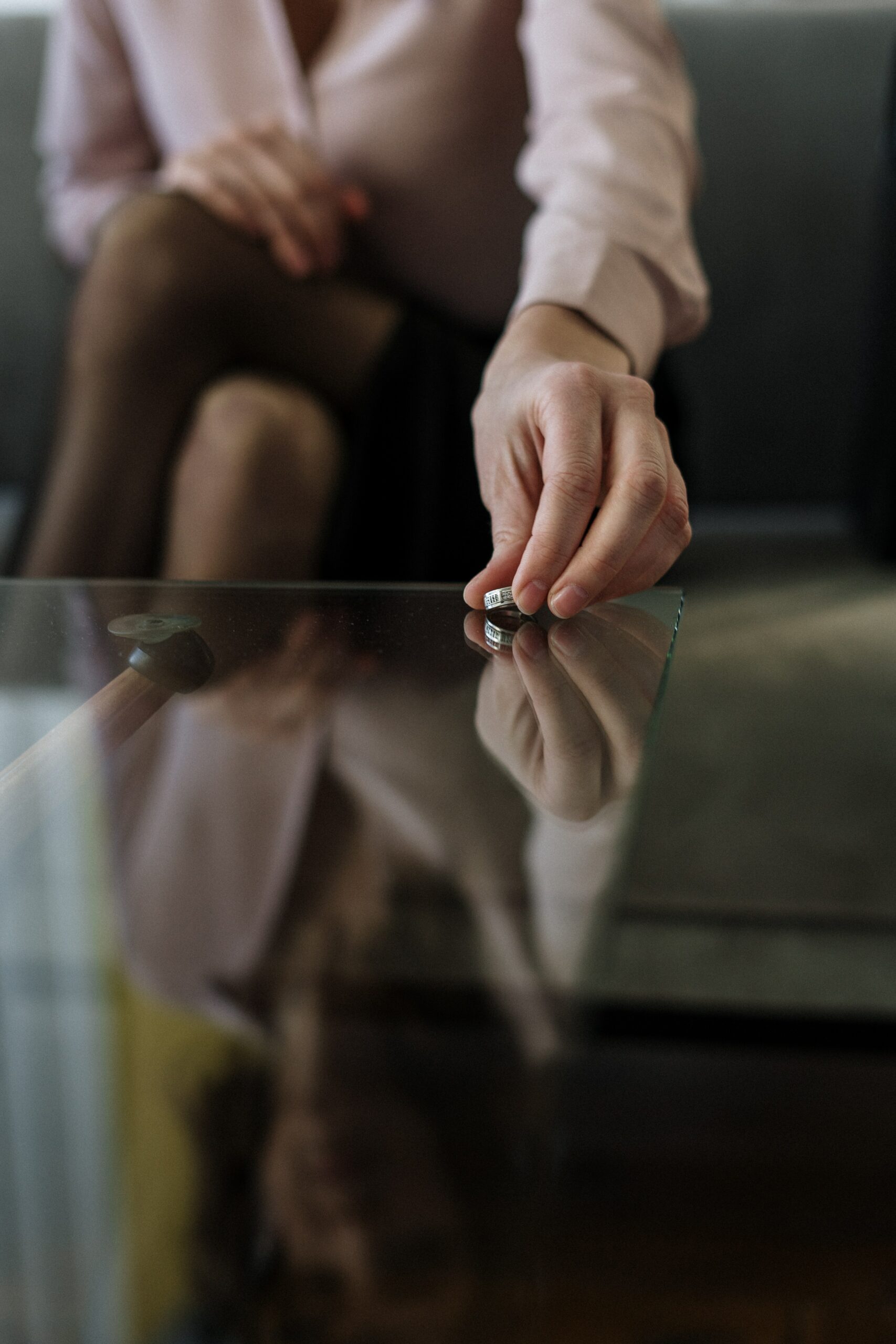 Man picking up ring from a reflective dark glass table