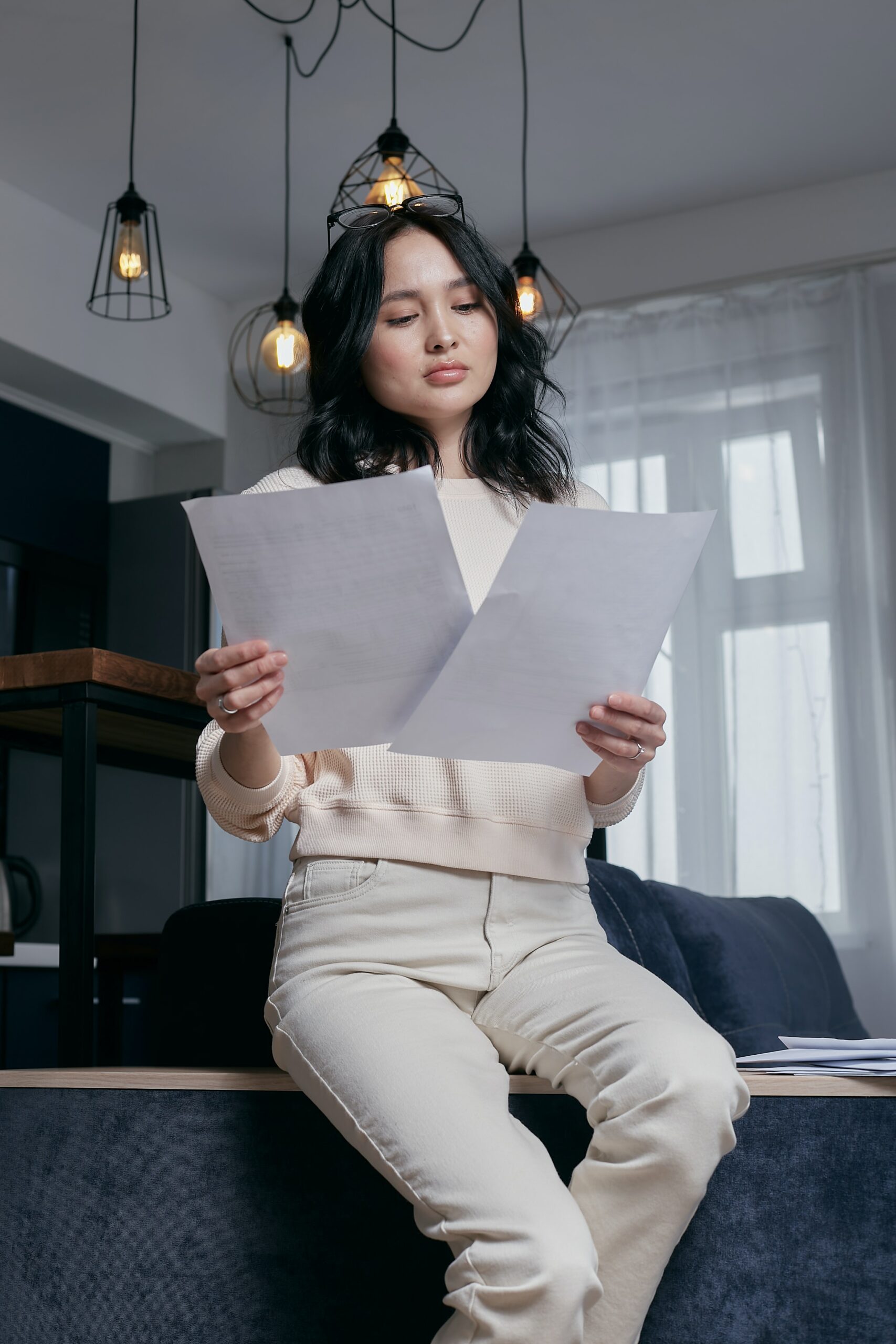 Lady reading through important two forms at once sat on the back of a sofa