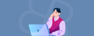 Thoughtful man sitting at an open laptop looking up with hand on chin against a slate blue background